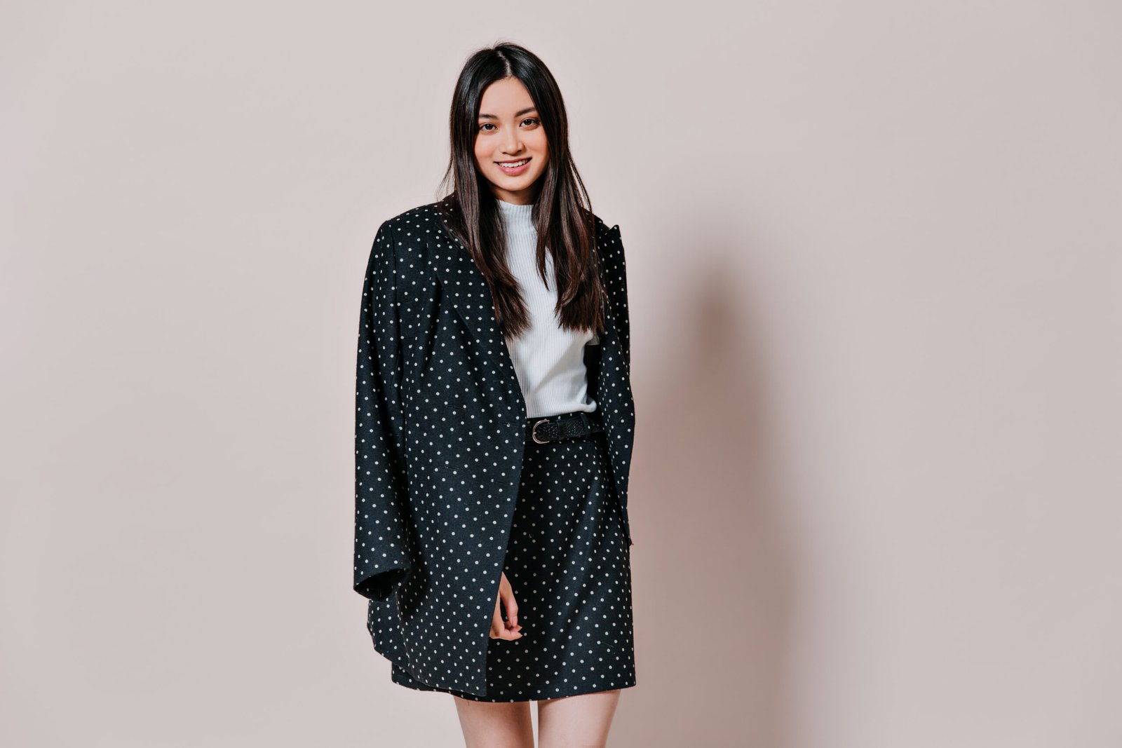 attractive woman suit polka dot smiles beige wall scaled